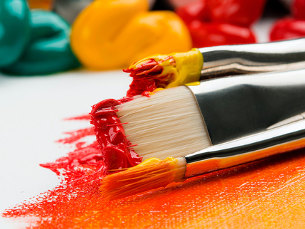Paint brushes with orange and yellow acrylic paint on