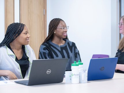 Tutor sitting speaking to two learners