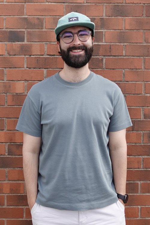 Adrian Rayworth stood against a brick wall, wearing a grey cap and t-shirt