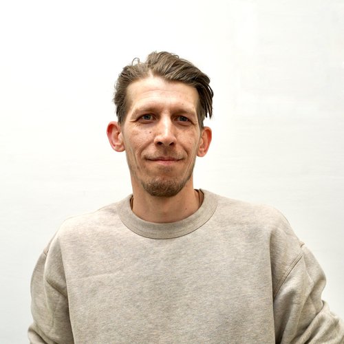A headshot image of a man wearing a grey jumper