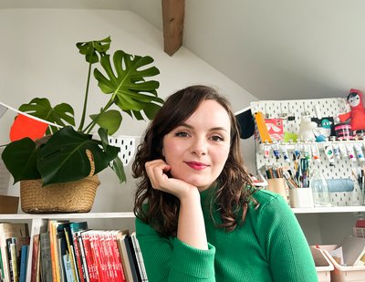 Photo of author Beth Woollvin: a white woman with dark brown hair wearing a green jumper
