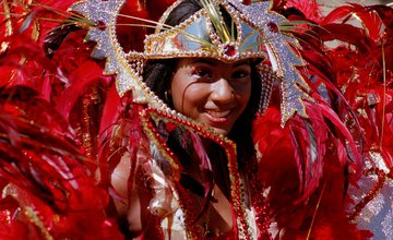 A lady smiling wearing traditional carnival dress of red feathers with sequins and glitter