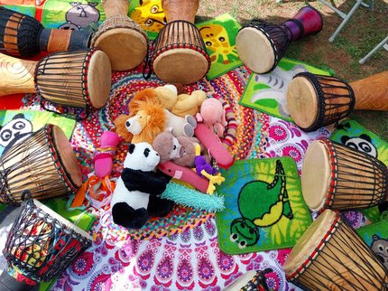 Photo of a circle of hand drums surrounding a pile of soft toy animals