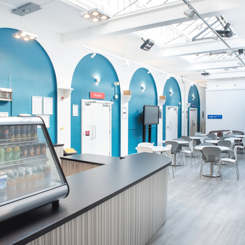 a cafe area with seating and a fridge full of drinks
