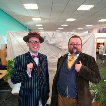 a photo of two white men dressed up in Edwardian clothing.