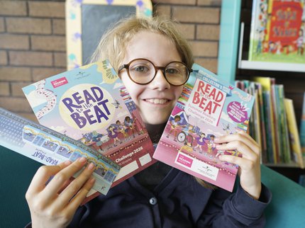 Young girl smiling with Summer Reading Challenge 2026 materials