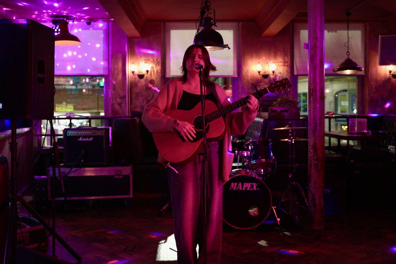 A young woman singing and playing the guitar