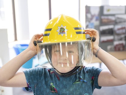 Young boy smiling and wearing an old fireman's helmet