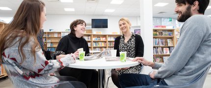 four adults talking and laughing around a table