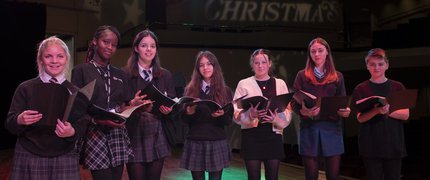A group of young singers in uniform on stage smiling