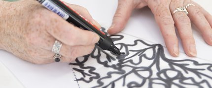 hands wearing rings drawing oak leaves in black biro
