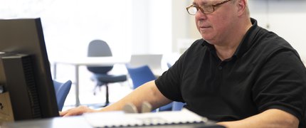 man sat reading a computer screen