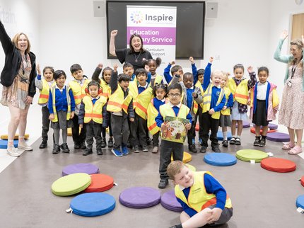 A group of children stand with an author in a library