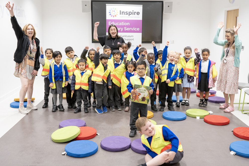 A group of children stand with an author in a library