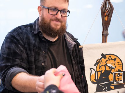 Man in a black shirt handing something to a shopper at a market