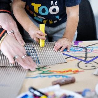 Child using a yellow paint stick on cardboard