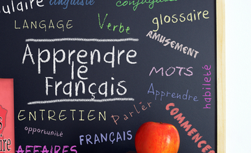 Chalkboard with French words, stack of books and an apple