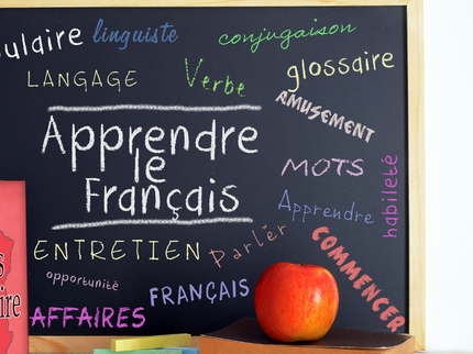Chalkboard with French words, stack of books and an apple