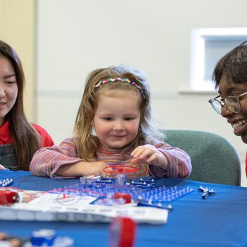 A young girl doing a snap circuits activity with two members of the Women in Engineering Society from the University of Sheffield