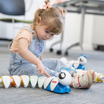 A young girl sitting on the floor playing with a code-a-pillar.