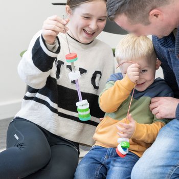 A girl, young boy and man sitting together for a creative floor-based activity.