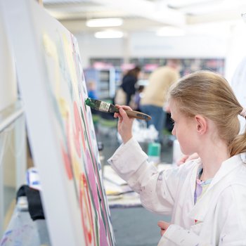 A girl painting at an easel.