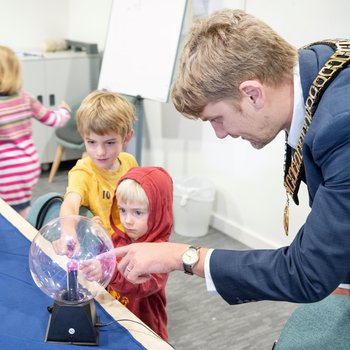 Two young children and a councillor pointing at a giant plasma ball,