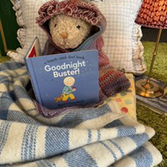 A toy teddy is wearing a Story Snuggler and reading a book