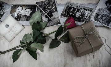 A collection of black and white family photos with a red rose and package