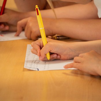 A close up of a child hand's hand writing