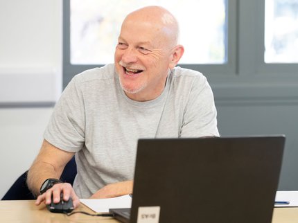 male learner at a laptop smiling