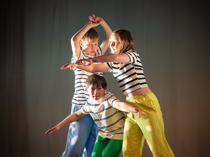 Three young dancers on stage wearing striped t shirts