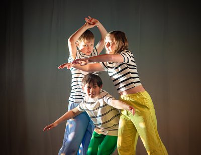 Three young dancers on stage wearing striped t shirts