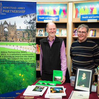 2 stallholders from Newstead Abbey Partnership standing with a banner and table top display of books.