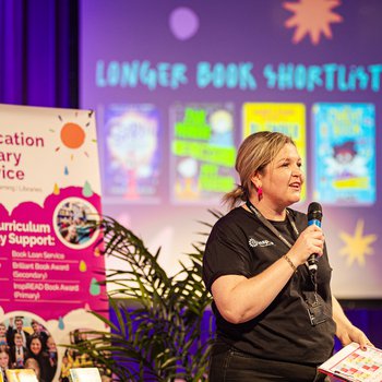 A woman stands with a microphone