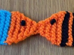 A knitted bookmark shaped like two fish, kissing