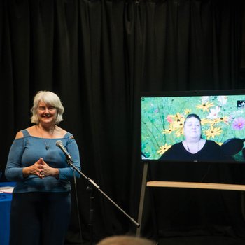 Photo of two of the Social Model Writers - one in person and one on a screen on Zoom