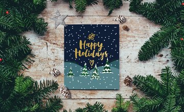 Lino printed card with gold text 'Happy Holidays' with snow covered trees