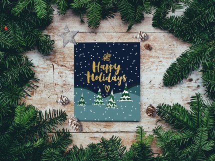 Lino printed card with gold text 'Happy Holidays' with snow covered trees