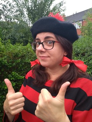 Photo of Cartoonist Laura Howell dressed as Minnie the Minx, in a red and black striped top and black beret.