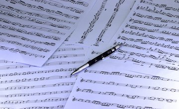Several pages of sheet music with a biro placed on top