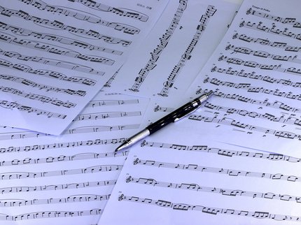 Several pages of sheet music with a biro placed on top
