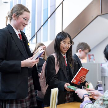 Two girls holding books gets their books signed by an author
