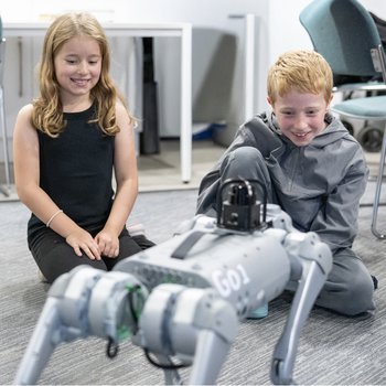 Girl and boy watching a robot dog