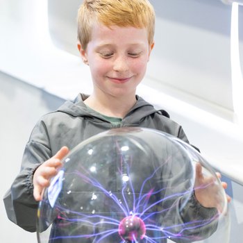 Boy touching plasma ball