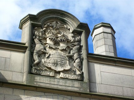 Stone work at the top of a building with a family coat of arms