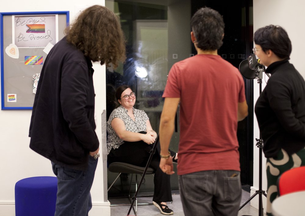 Photograph of interviewee seated in front of a three-person camera crew