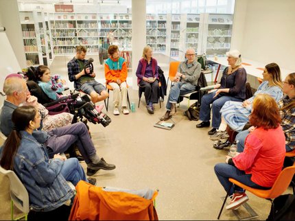 Photo of people sitting in a circle of chairs in a library