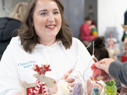 Stallholder in a white hoodie smiling at shoppers