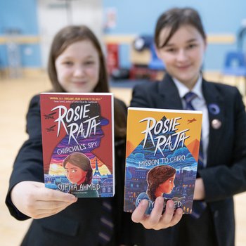 three school children hold copies of Rosie Raja the book